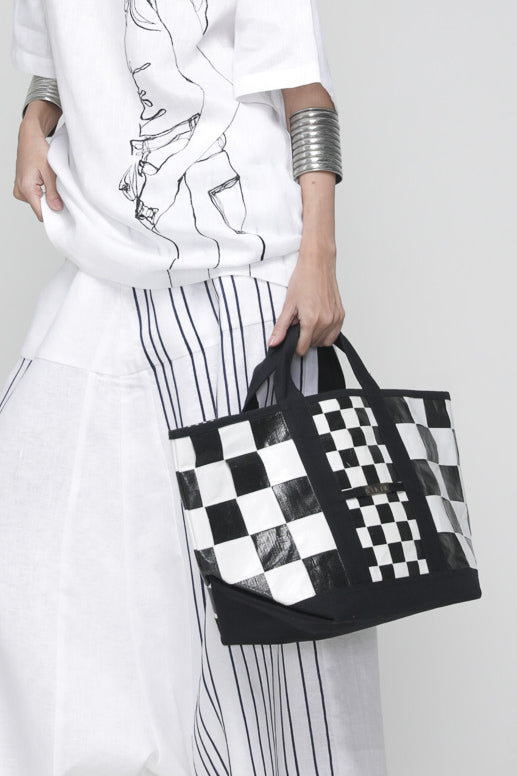 Black and white checkered terpal tote bag with canvas straps, cotton block print accent, and internal pocket.