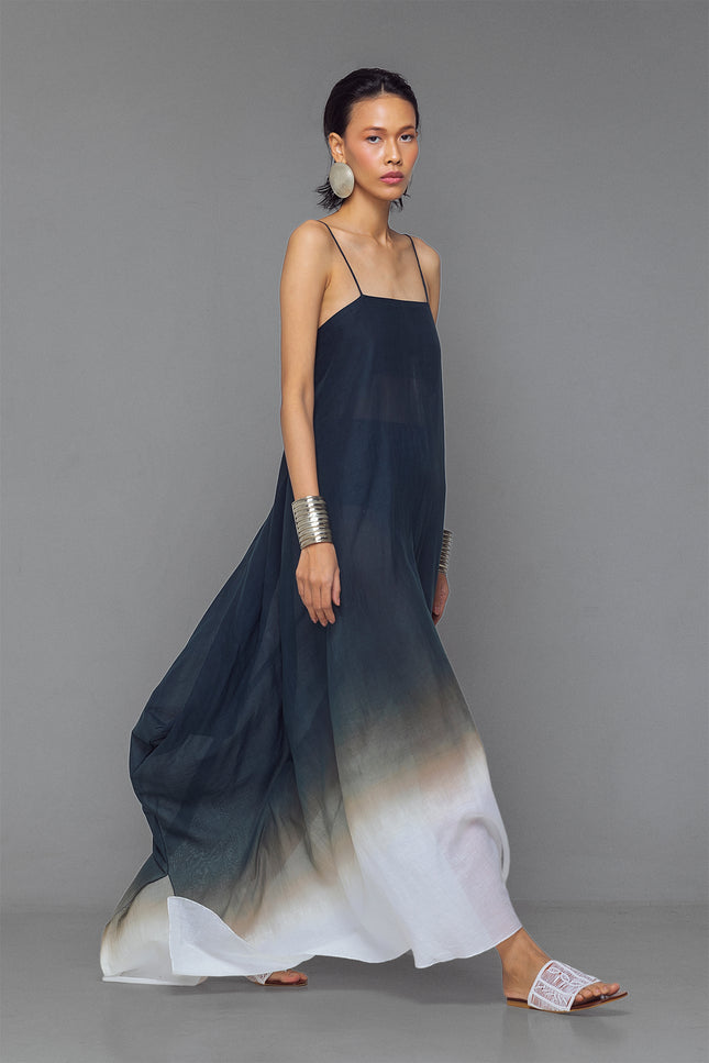 Model wearing black and white dip-dye cotton dress with criss-cross straps and flowy adjustable silhouette.
