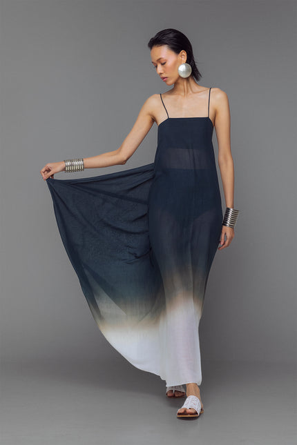 Model wearing black and white dip-dye cotton dress with criss-cross straps and flowy adjustable silhouette.