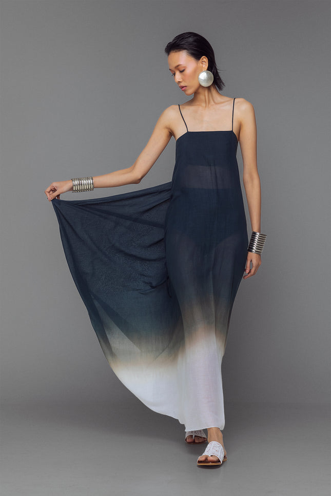 Model wearing black and white dip-dye cotton dress with criss-cross straps and flowy adjustable silhouette.