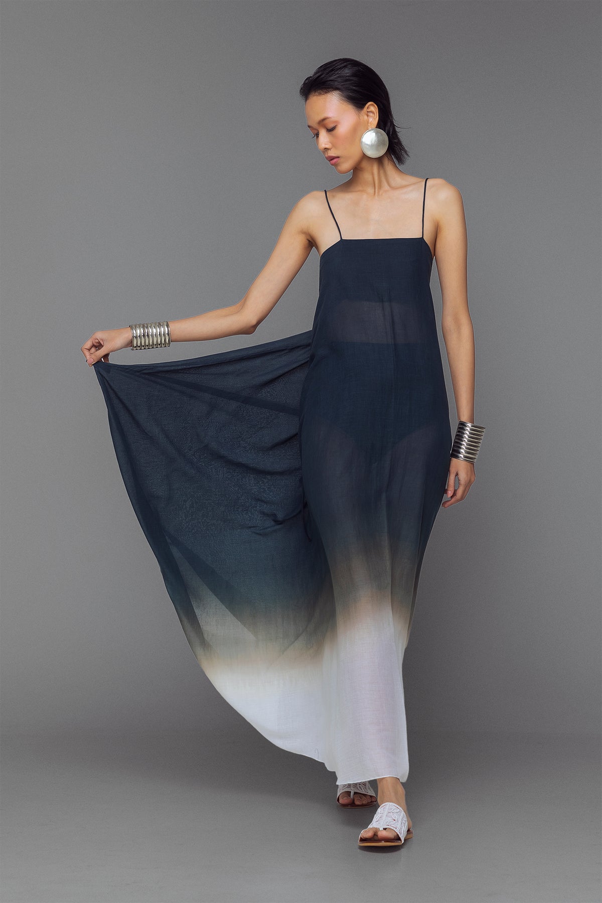 Model wearing black and white dip-dye cotton dress with criss-cross straps and flowy adjustable silhouette.