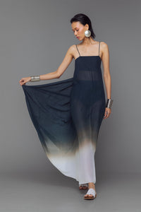 Model wearing black and white dip-dye cotton dress with criss-cross straps and flowy adjustable silhouette.