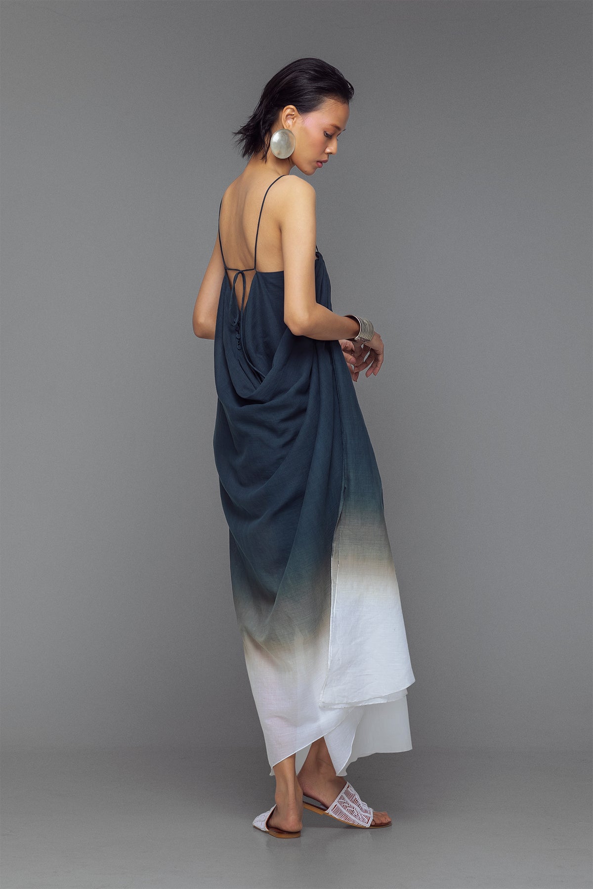 Model wearing black and white dip-dye cotton dress with criss-cross straps and flowy adjustable silhouette.
