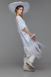 Model wearing white cotton kaftan with stripe appliqué and handmade fringe, styled for summer.