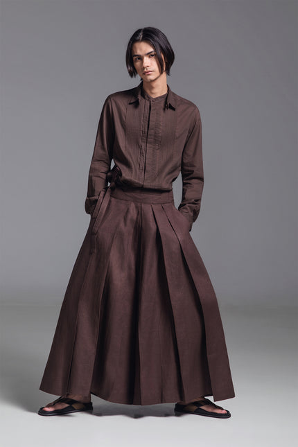 Model wearing wide pleated linen pants with deep front pleats, side zipper, and fixed waist belt detail.
