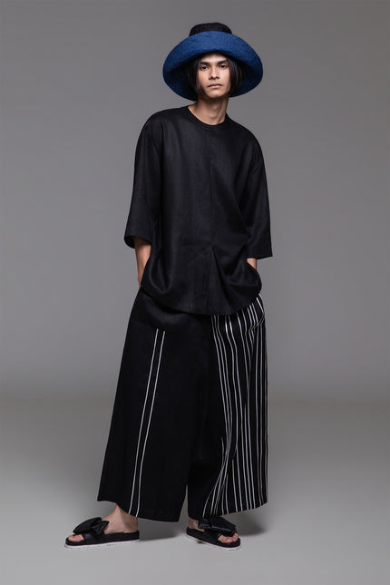 Model wearing Ondre tunic tee with an oversized silhouette, collarless round neckline, front pleat detailing, and mixed linen and jersey construction.