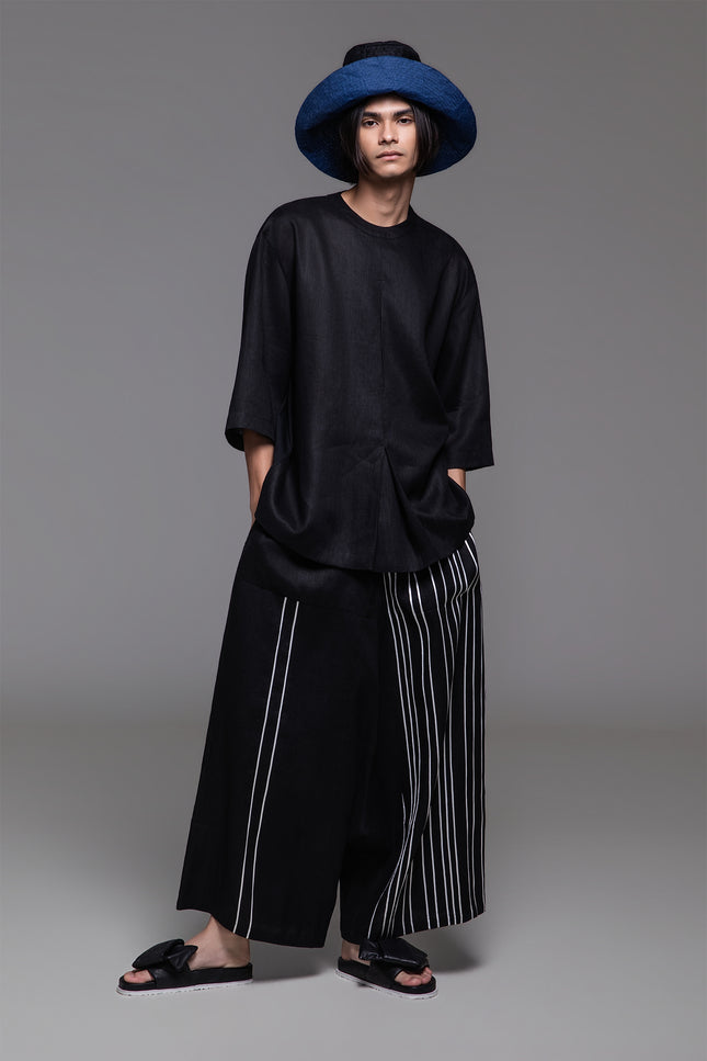 Model wearing Ondre tunic tee with an oversized silhouette, collarless round neckline, front pleat detailing, and mixed linen and jersey construction.
