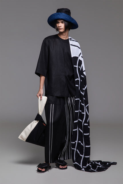 Model wearing Ondre tunic tee with an oversized silhouette, collarless round neckline, front pleat detailing, and mixed linen and jersey construction.