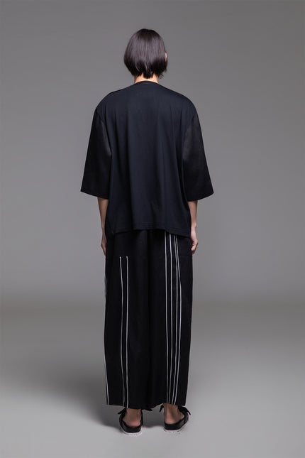 Model wearing Ondre tunic tee with an oversized silhouette, collarless round neckline, front pleat detailing, and mixed linen and jersey construction.