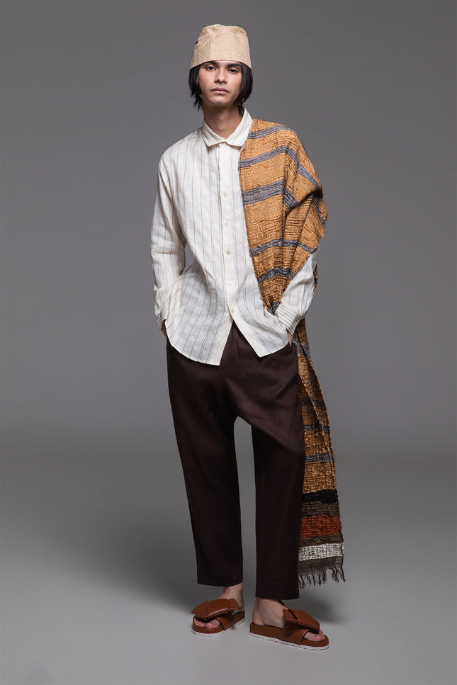 Model wearing white linen shirt with contrast stitching, long sleeves, and curved hemline, styled for a relaxed tailored look.