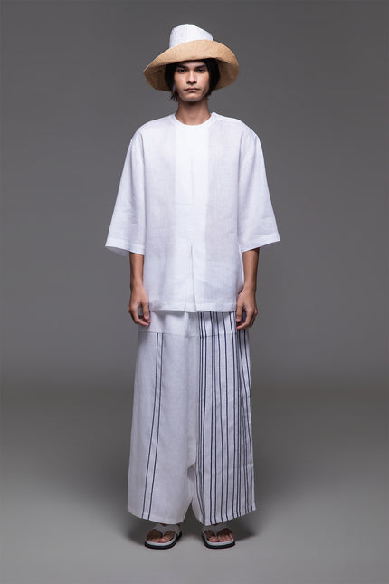 Model wearing Ondre tunic tee with an oversized silhouette, collarless round neckline, front pleat detailing, and mixed linen and jersey construction.