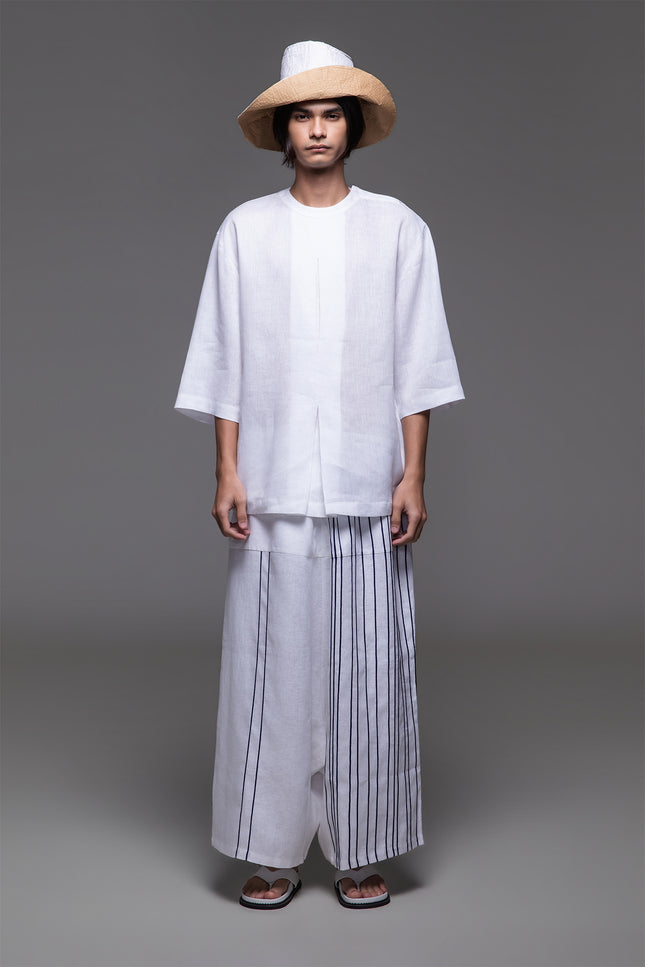 Model wearing Ondre tunic tee with an oversized silhouette, collarless round neckline, front pleat detailing, and mixed linen and jersey construction.