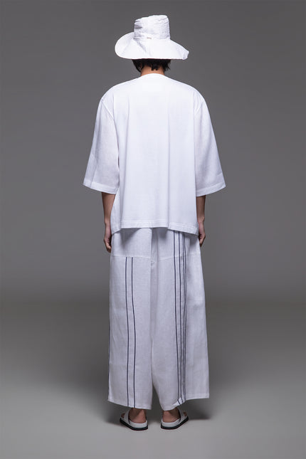 Model wearing Ondre tunic tee with an oversized silhouette, collarless round neckline, front pleat detailing, and mixed linen and jersey construction.