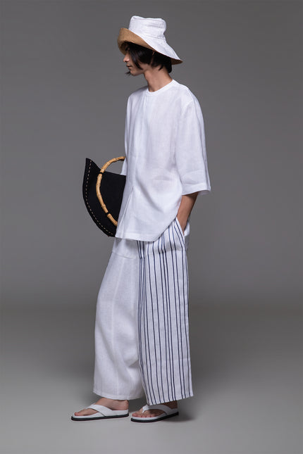 Model wearing Ondre tunic tee with an oversized silhouette, collarless round neckline, front pleat detailing, and mixed linen and jersey construction.