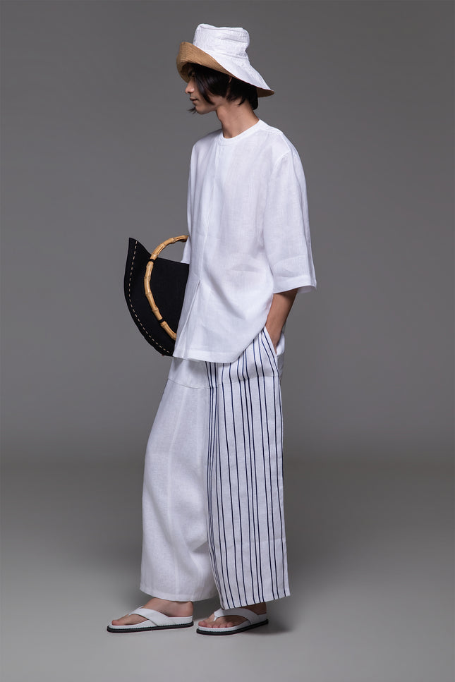 Model wearing Ondre tunic tee with an oversized silhouette, collarless round neckline, front pleat detailing, and mixed linen and jersey construction.