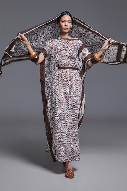 Model wearing Olva Kaftan in lightweight cotton with artisanal patchwork side panel, fringed neckline, flowing rectangular silhouette with side slit, and detachable belt, featuring intricate handcrafted details.