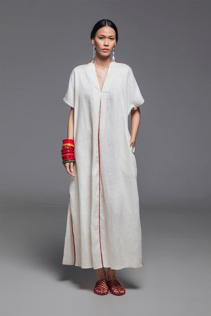 Model wearing Odis Kaftan in pure linen, featuring a loose silhouette with clean lines, V-neckline, side slit, contrast binding, and neutral palette, perfect for a relaxed resort wear.