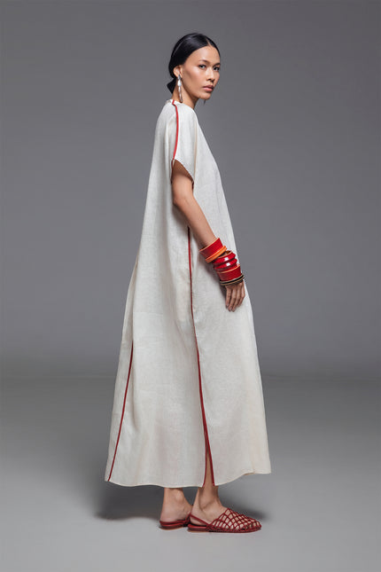 Model wearing Odis Kaftan in pure linen, featuring a loose silhouette with clean lines, V-neckline, side slit, contrast binding, and neutral palette, perfect for a relaxed resort wear.