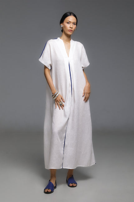 Model wearing Odis Kaftan in pure linen, featuring a loose silhouette with clean lines, V-neckline, side slit, contrast binding, and neutral palette, perfect for a relaxed resort wear.