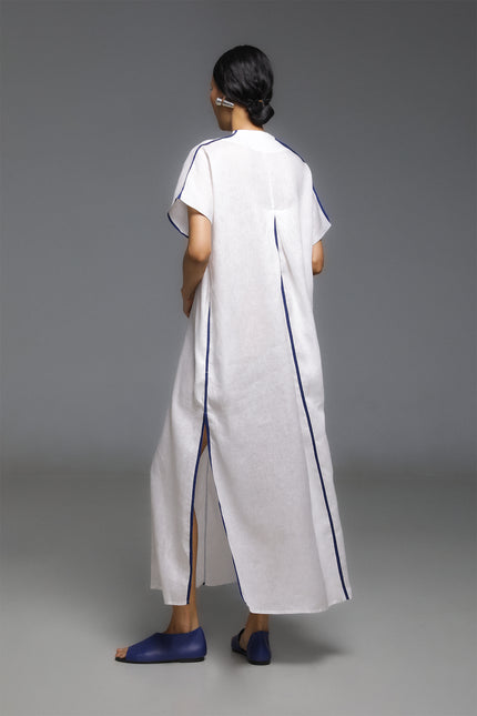 Model wearing Odis Kaftan in pure linen, featuring a loose silhouette with clean lines, V-neckline, side slit, contrast binding, and neutral palette, perfect for a relaxed resort wear.