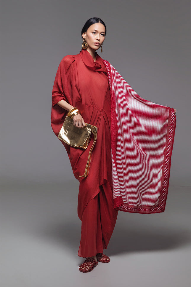 Model wearing Ozella Kaftan with contemporary silhouette, high neckline, sculptural drapery, and contrasting asymmetrical hem for a sophisticated look.