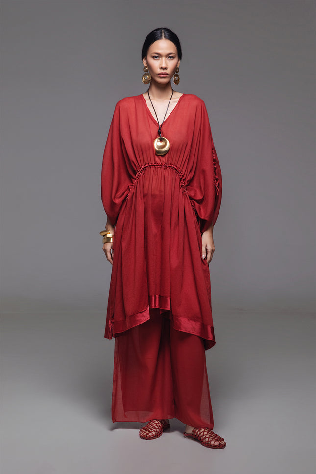 Model wearing the Noelia Dress with an adjustable drawstring shaping, V-neckline, voluminous silhouette, and silk hem border with subtle transparency for an elegant look.