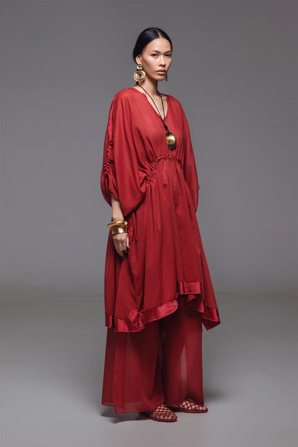 Model wearing the Noelia Dress with an adjustable drawstring shaping, V-neckline, voluminous silhouette, and silk hem border with subtle transparency for an elegant look.