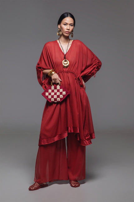 Model wearing the Noelia Dress with an adjustable drawstring shaping, V-neckline, voluminous silhouette, and silk hem border with subtle transparency for an elegant look.