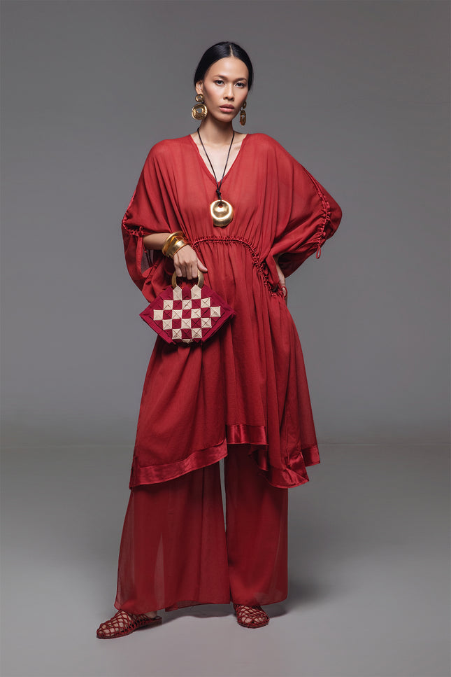 Model wearing the Noelia Dress with an adjustable drawstring shaping, V-neckline, voluminous silhouette, and silk hem border with subtle transparency for an elegant look.