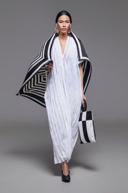Model wearing Naria Kaftan in light cotton with floor-length straight silhouette, full vertical pleats, and V-neckline for a clean, architectural look.