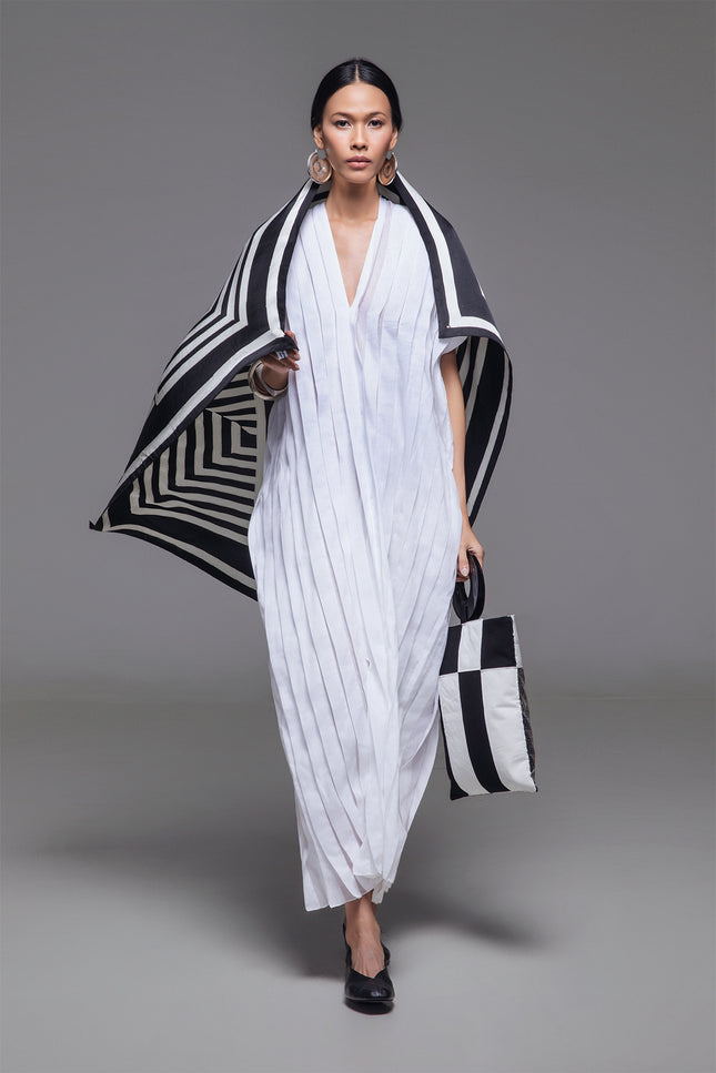 Model wearing Naria Kaftan in light cotton with floor-length straight silhouette, full vertical pleats, and V-neckline for a clean, architectural look.