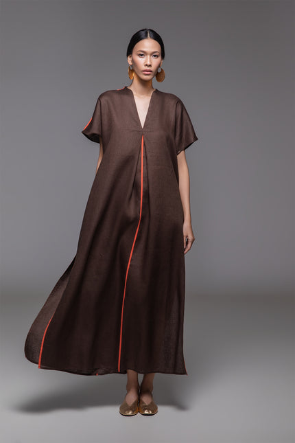 Model wearing Odis Kaftan in pure linen, featuring a loose silhouette with clean lines, V-neckline, side slit, contrast binding, and neutral palette, perfect for a relaxed resort wear.