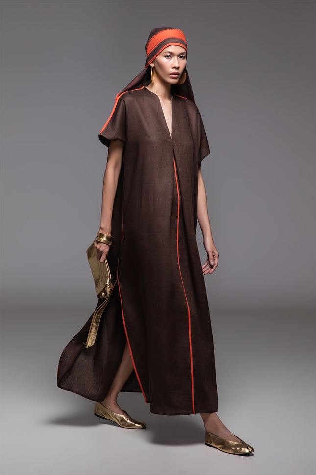 Model wearing Odis Kaftan in pure linen, featuring a loose silhouette with clean lines, V-neckline, side slit, contrast binding, and neutral palette, perfect for a relaxed resort wear.