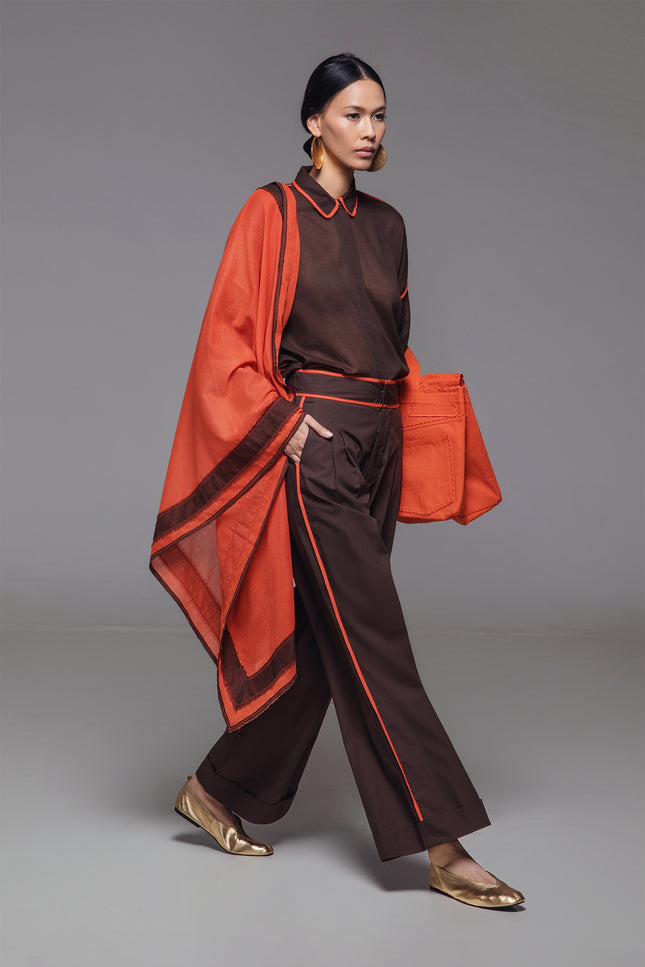 Model wearing Neal Pants in lightweight cotton, featuring a high waist, full-length silhouette, front pleats, cuffed hem, and contrast piping detail.