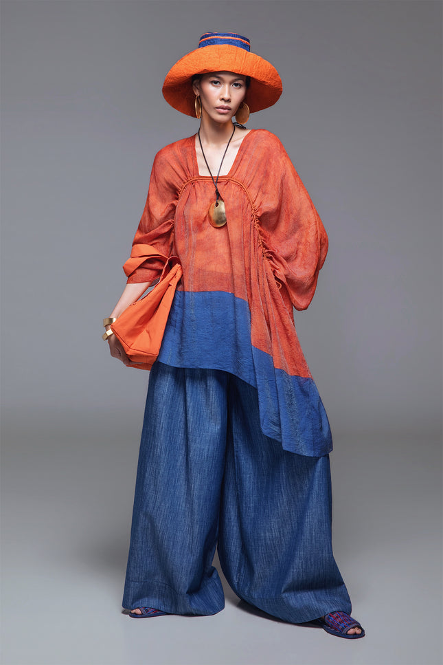 Model wearing BIASA Orrel Tunic with a relaxed voluminous silhouette, square neckline, adjustable drawstrings, and two-tone cotton design.