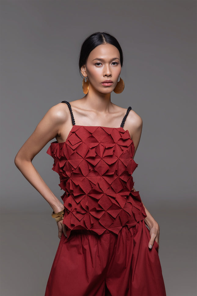Model wearing Omaria Top in lightweight cotton, featuring an all-over geometric pleated texture and adjustable braided shoulder straps.