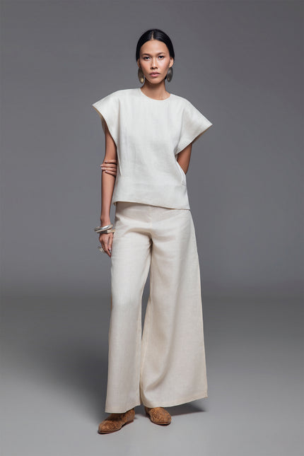 Model wearing Norina Top in light linen, featuring a structured sleeveless silhouette with wide shoulders and a rounded neckline.