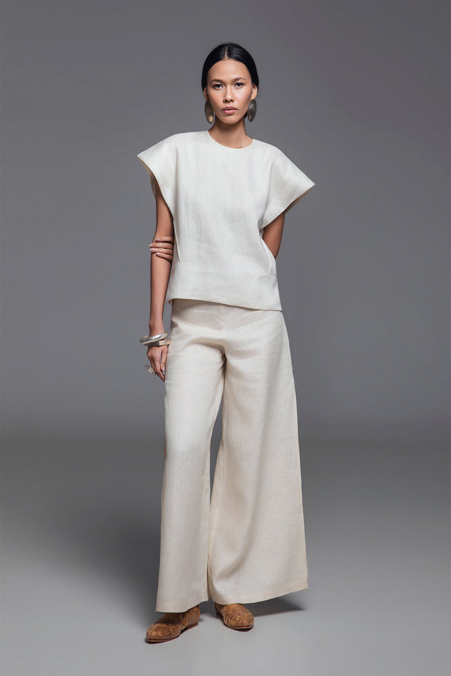 Model wearing Norina Top in light linen, featuring a structured sleeveless silhouette with wide shoulders and a rounded neckline.