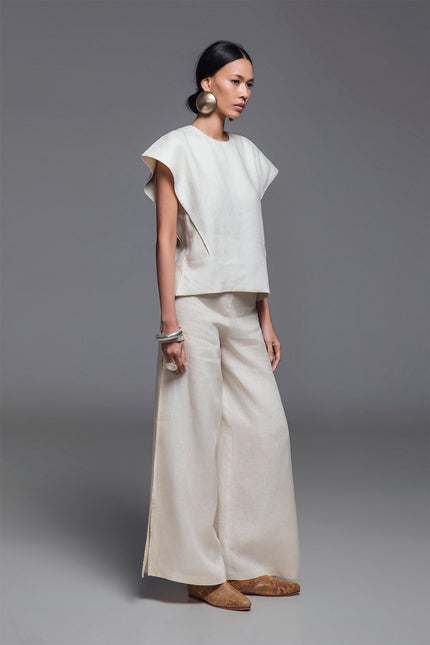 Model wearing Norina Top in light linen, featuring a structured sleeveless silhouette with wide shoulders and a rounded neckline.