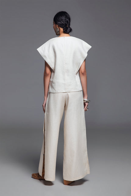 Model wearing Norina Top in light linen, featuring a structured sleeveless silhouette with wide shoulders and a rounded neckline.