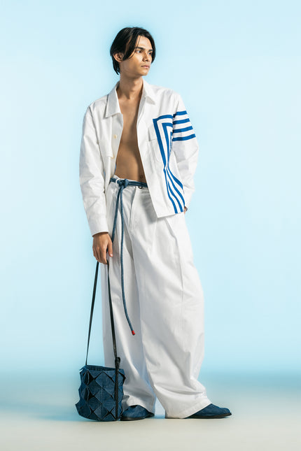 Model wearing Oskar Shirt Jacket in heavy cotton, featuring a boxy silhouette, blue hand-cut appliqué, concealed button placket, and side slits.