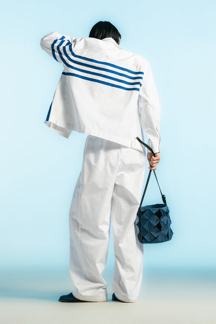 Model wearing Oskar Shirt Jacket in heavy cotton, featuring a boxy silhouette, blue hand-cut appliqué, concealed button placket, and side slits.