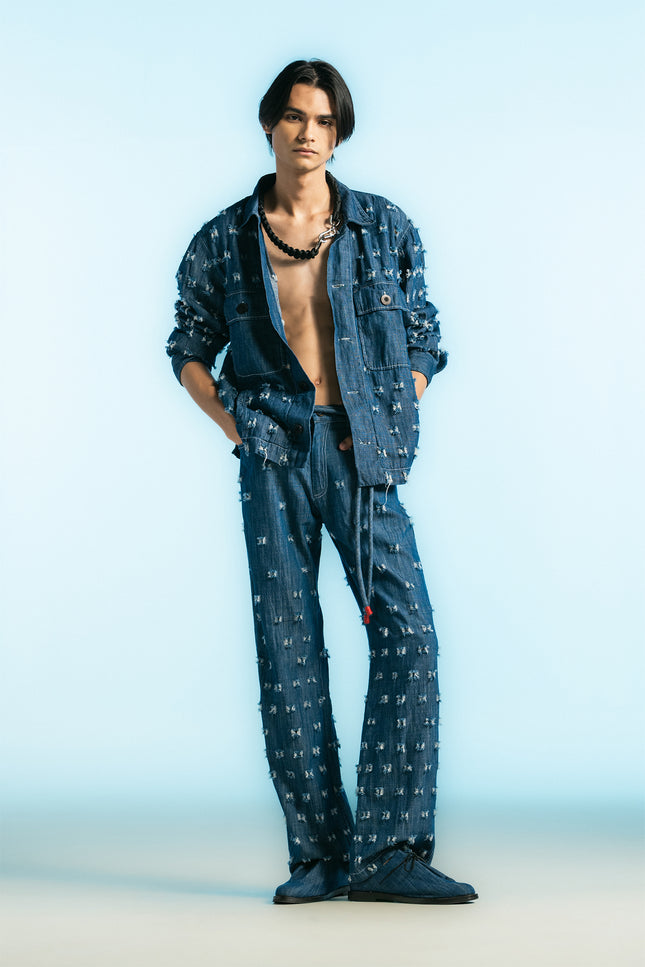 Model wearing the Olwen Jacket in 100% cotton, featuring a boxy silhouette, button-front closure, four pockets, and raw, textured denim with uneven threads.
