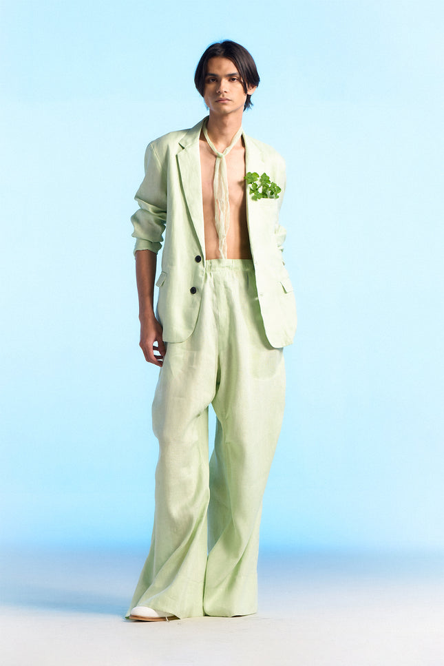 Model wearing Capri Jacket in 100% linen, featuring a slim silhouette, two-button front closure, subtle dotted edge stitching, curved hem, and buttoned cuffs.
