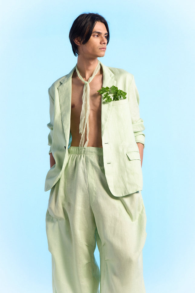 Model wearing Capri Jacket in 100% linen, featuring a slim silhouette, two-button front closure, subtle dotted edge stitching, curved hem, and buttoned cuffs.