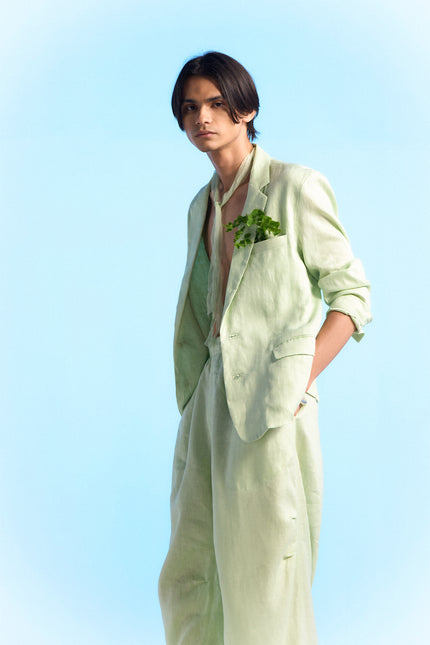 Model wearing Capri Jacket in 100% linen, featuring a slim silhouette, two-button front closure, subtle dotted edge stitching, curved hem, and buttoned cuffs.