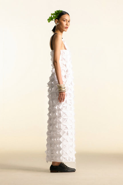 Model wearing Oana Origami Dress in pure cotton, featuring geometric pleats, hand-folded origami texture, and braided straps for a sculptural silhouette.