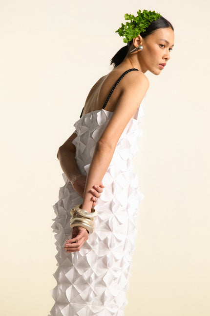 Model wearing Oana Origami Dress in pure cotton, featuring geometric pleats, hand-folded origami texture, and braided straps for a sculptural silhouette.