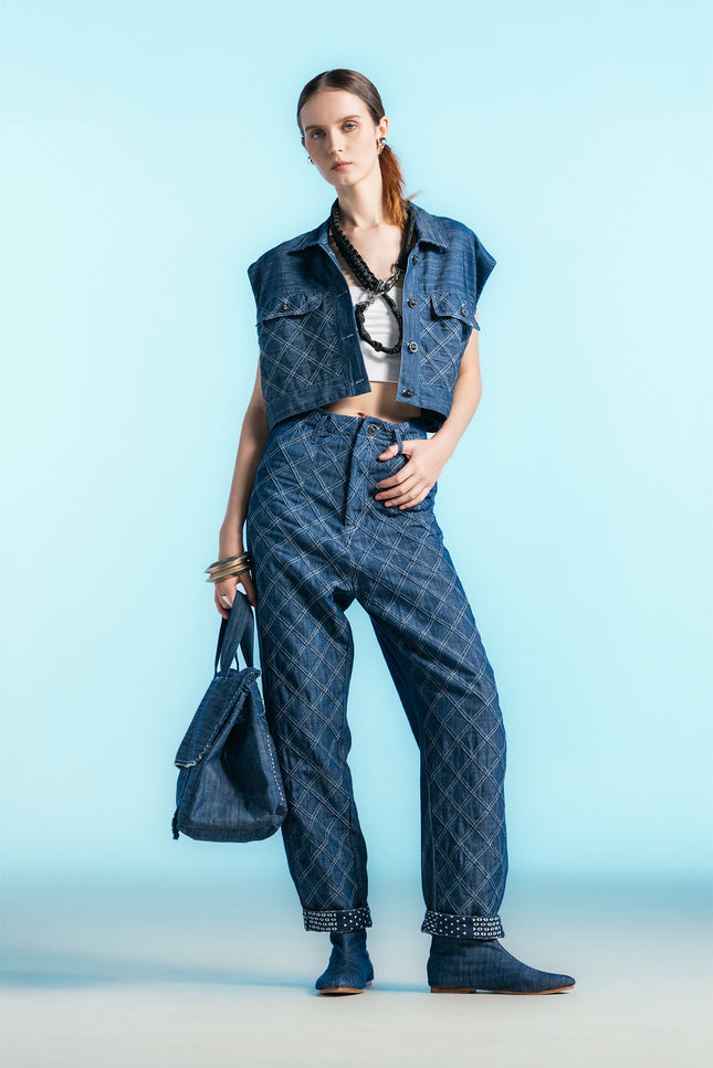 Model wearing Nena Jacket in cotton denim, featuring a cropped sleeveless silhouette and diamond-patch textured detailing.