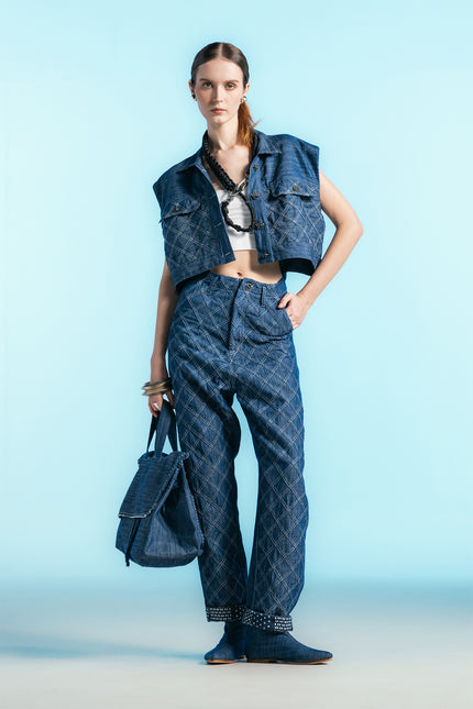 Model wearing Nena Jacket in cotton denim, featuring a cropped sleeveless silhouette and diamond-patch textured detailing.